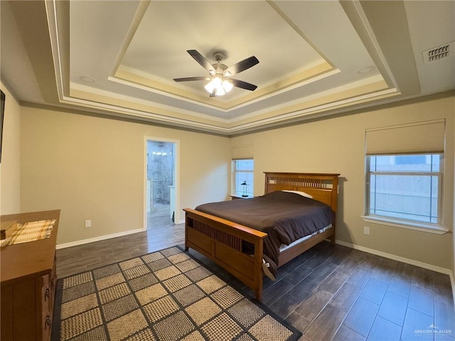 bedroom featuring ensuite bathroom, a raised ceiling, and ceiling fan