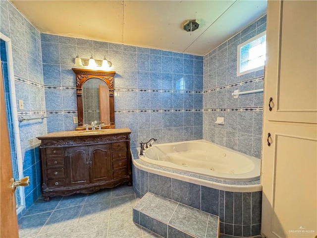 bathroom with a jetted tub, vanity, tile walls, and tile patterned floors