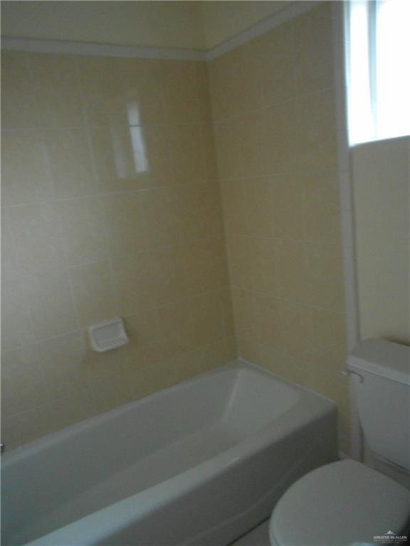 bathroom featuring tiled shower / bath combo and toilet