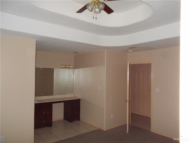 interior space featuring ceiling fan, built in desk, and light tile patterned floors