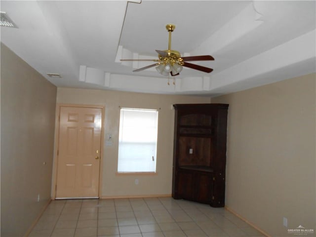 entrance foyer with light tile patterned floors, a tray ceiling, and ceiling fan