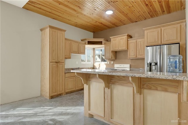 kitchen featuring light stone countertops, stainless steel fridge, white range, light colored carpet, and light brown cabinets