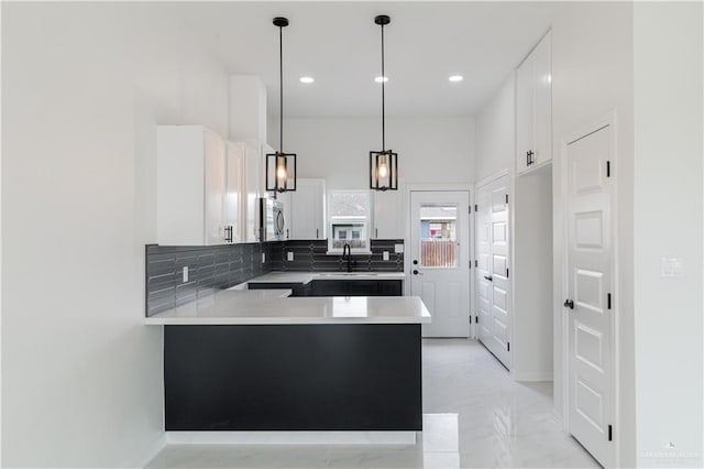 kitchen with sink, hanging light fixtures, kitchen peninsula, decorative backsplash, and white cabinets