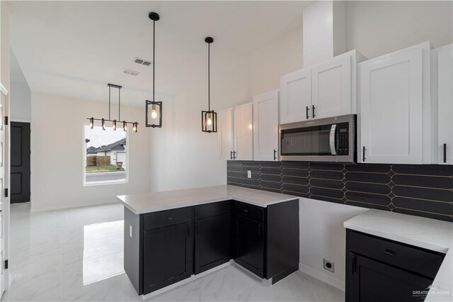 kitchen featuring kitchen peninsula, decorative backsplash, white cabinets, and hanging light fixtures