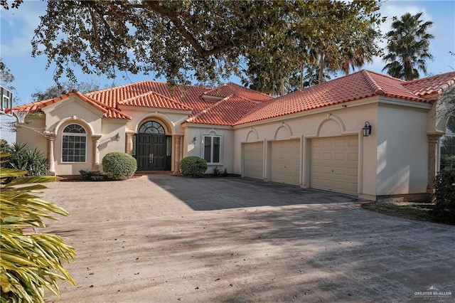 mediterranean / spanish-style home featuring a garage, driveway, and a tile roof