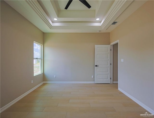 unfurnished room with a raised ceiling, ceiling fan, and light hardwood / wood-style flooring