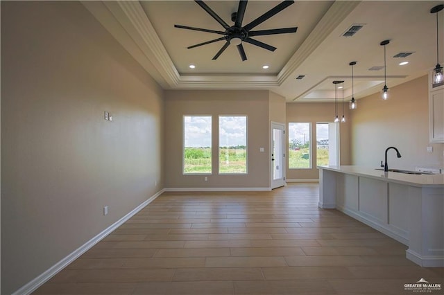 kitchen featuring ceiling fan, sink, light hardwood / wood-style flooring, decorative light fixtures, and a tray ceiling