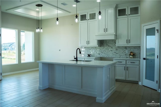 kitchen featuring white cabinetry, sink, decorative light fixtures, and a center island with sink