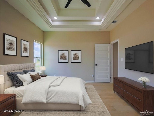 bedroom featuring ceiling fan, light wood-type flooring, and a tray ceiling