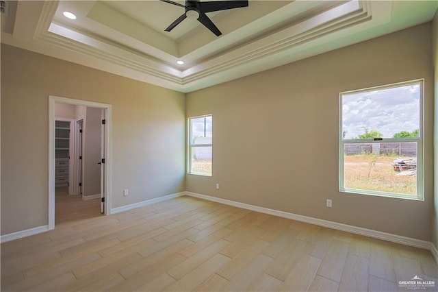 unfurnished room featuring ceiling fan, light hardwood / wood-style floors, and a raised ceiling