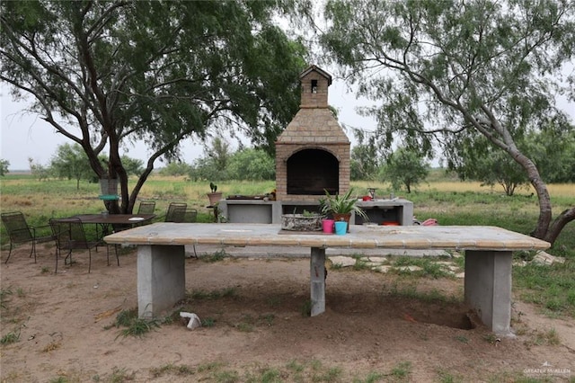 exterior space featuring an outdoor brick fireplace, a rural view, and a patio