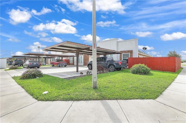 view of vehicle parking featuring a lawn and a carport