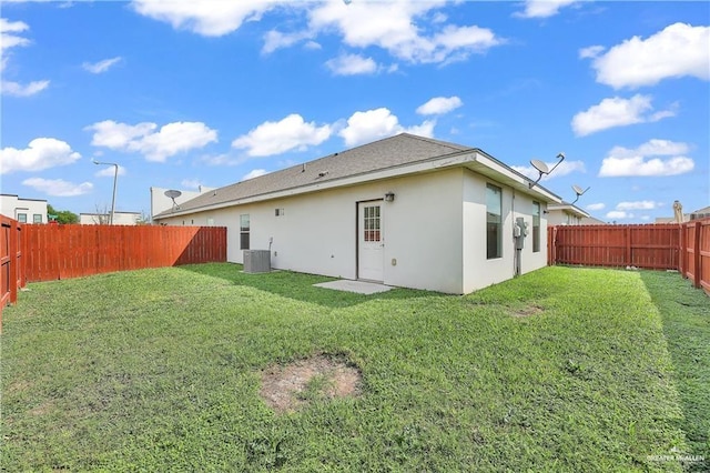 rear view of property with a lawn and central AC