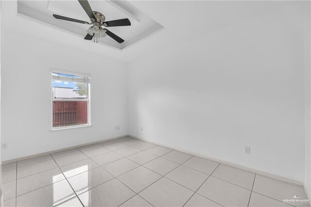 unfurnished room with a tray ceiling, ceiling fan, and light tile patterned flooring