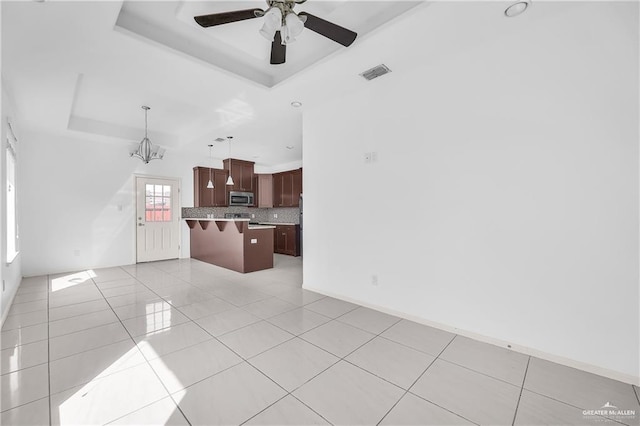 living room with a raised ceiling, light tile patterned floors, and ceiling fan with notable chandelier