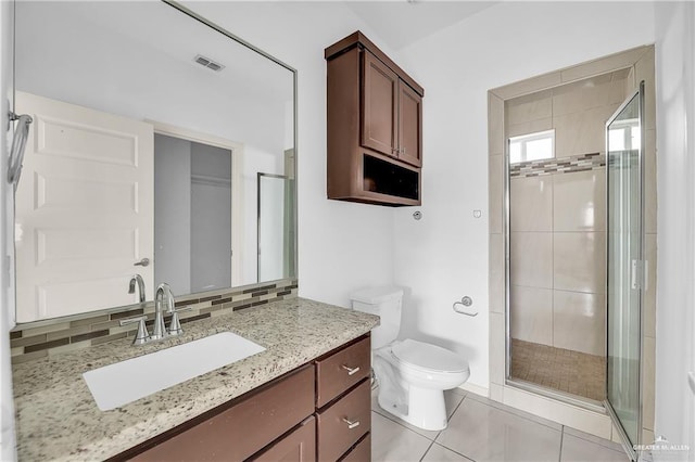 bathroom featuring backsplash, tile patterned floors, walk in shower, vanity, and toilet