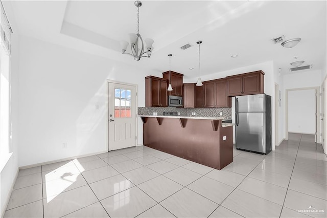 kitchen with backsplash, decorative light fixtures, a notable chandelier, a kitchen bar, and stainless steel appliances