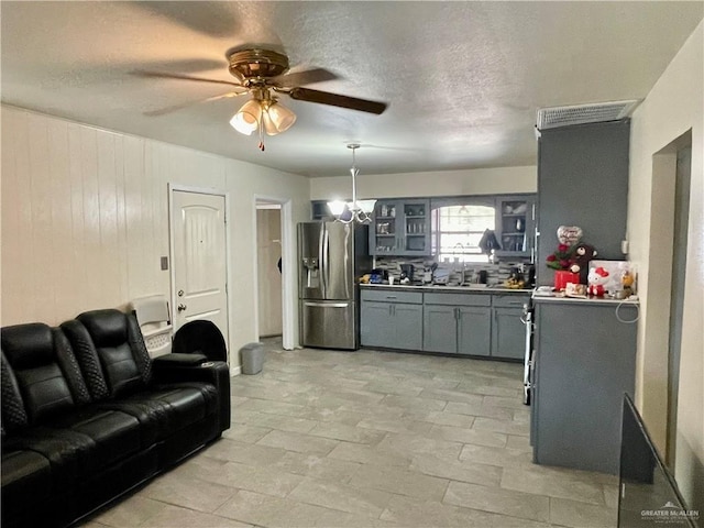 kitchen featuring visible vents, glass insert cabinets, gray cabinets, stainless steel refrigerator with ice dispenser, and a sink