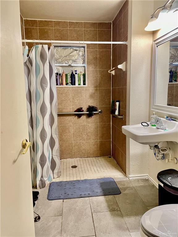 full bath with a tile shower and toilet