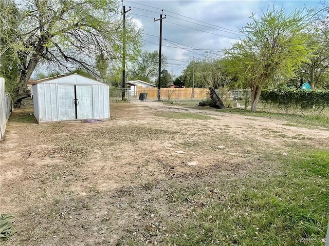 view of yard with fence, a storage unit, and an outdoor structure