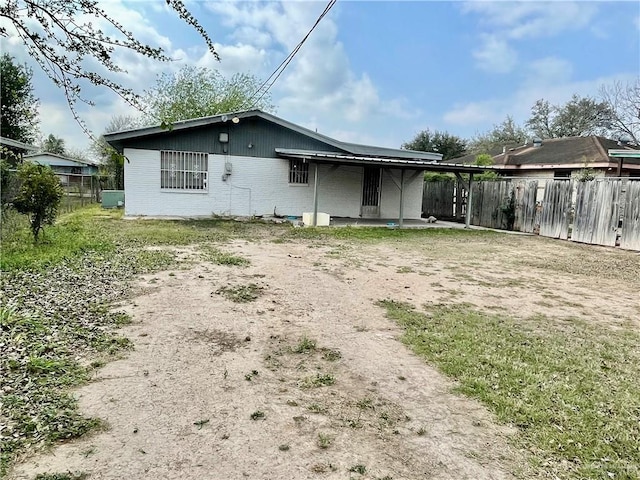 rear view of house with brick siding and fence