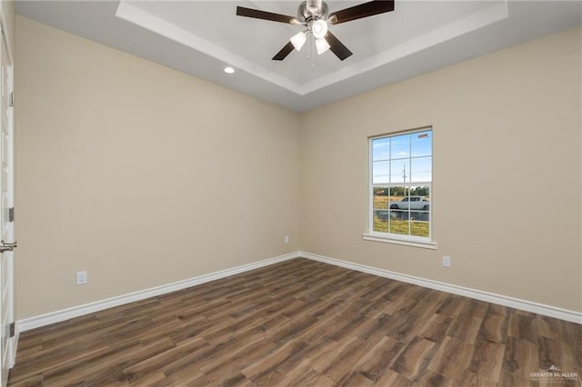 spare room with a raised ceiling, ceiling fan, and dark wood-type flooring