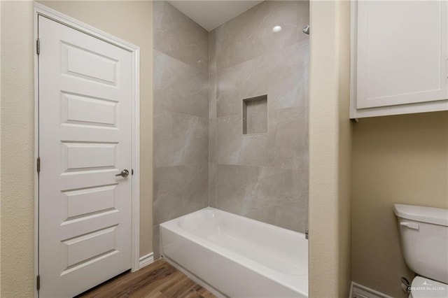 bathroom with hardwood / wood-style floors, tiled shower / bath combo, and toilet