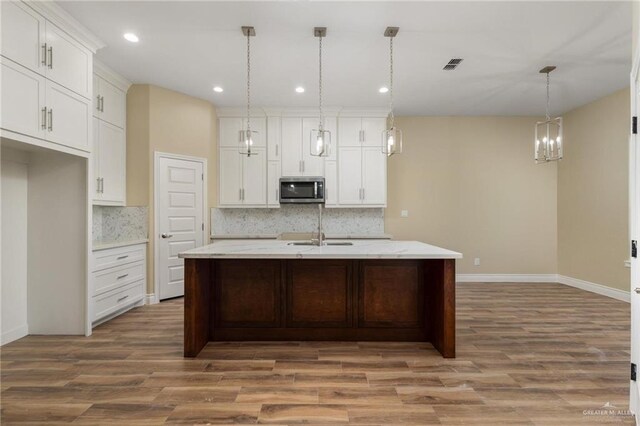 16619 Napper Ln, Harlingen, TX 78552 - kitchen featuring stainless steel microwave, wood finished floors, tasteful backsplash, and recessed lighting