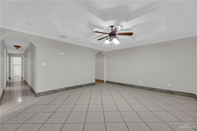 tiled spare room with a tray ceiling and ceiling fan