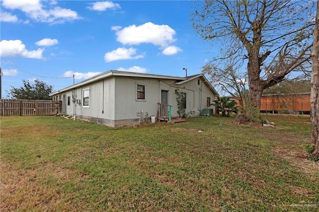 rear view of property with a yard and central air condition unit