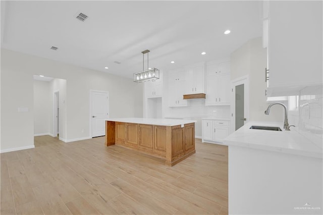 2205 Cardinal Dr, Weslaco, TX 78596 - kitchen featuring tasteful backsplash, white cabinets, light wood finished floors, recessed lighting, and hanging light fixtures