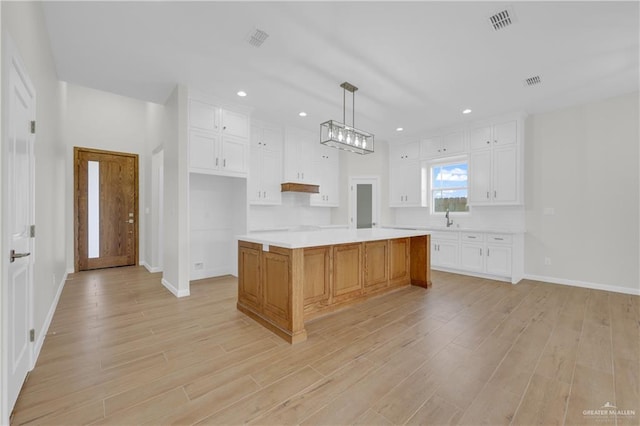 2205 Cardinal Dr, Weslaco, TX 78596 - kitchen with white cabinets, light countertops, light wood finished floors, a kitchen island, and recessed lighting