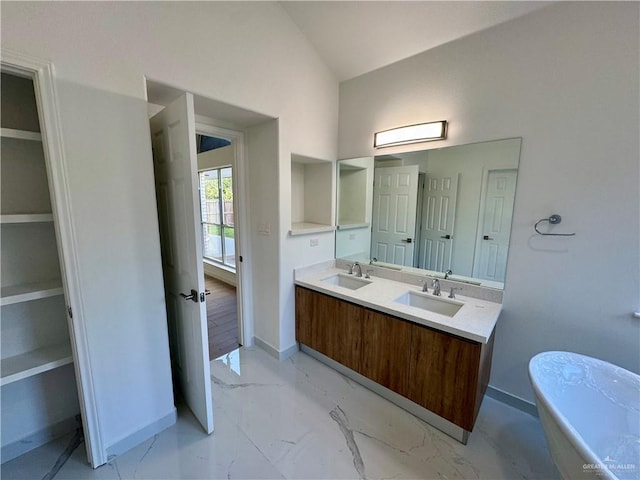 bathroom featuring vanity, vaulted ceiling, and a tub