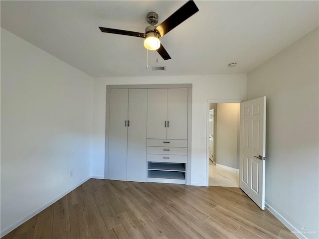 unfurnished bedroom with ceiling fan, light wood-type flooring, and a closet