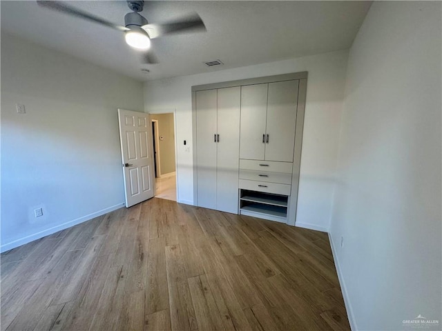 unfurnished bedroom featuring ceiling fan, light wood-type flooring, and a closet