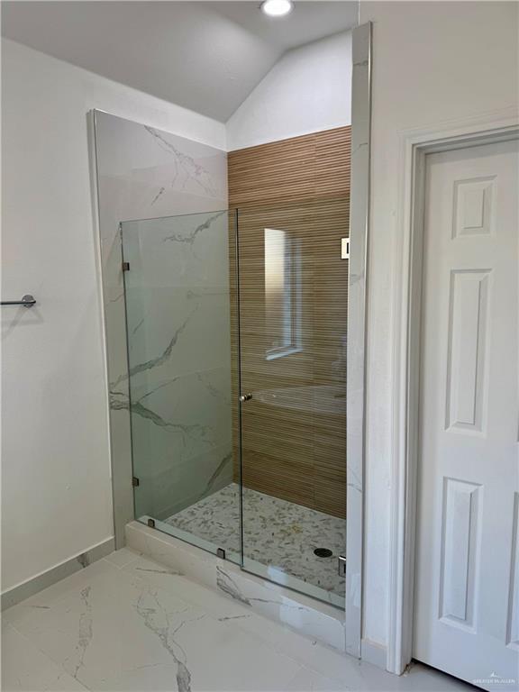 bathroom with vaulted ceiling and a shower with door