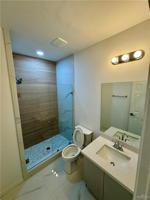 bathroom with vanity, toilet, and a shower with door