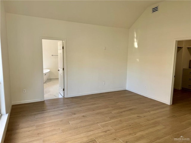 empty room with light hardwood / wood-style flooring and vaulted ceiling