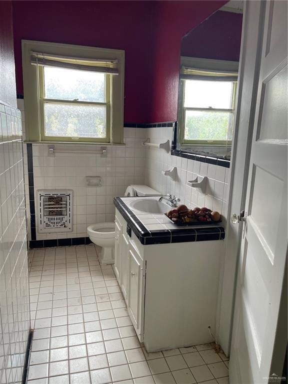 bathroom featuring vanity, heating unit, tile walls, tile patterned flooring, and toilet