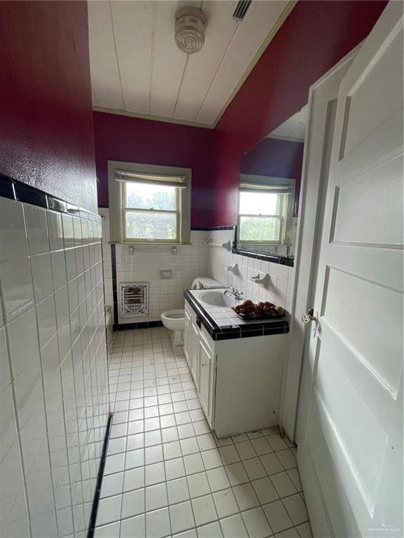 bathroom featuring tile patterned flooring, heating unit, tile walls, and a healthy amount of sunlight