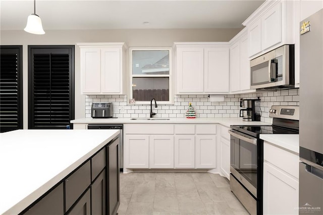 kitchen featuring white cabinetry, sink, hanging light fixtures, and appliances with stainless steel finishes