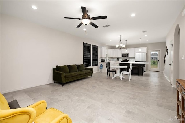 living room featuring ceiling fan with notable chandelier