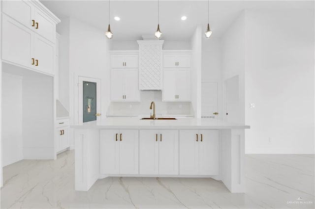 kitchen with a center island with sink, decorative light fixtures, white cabinets, and sink