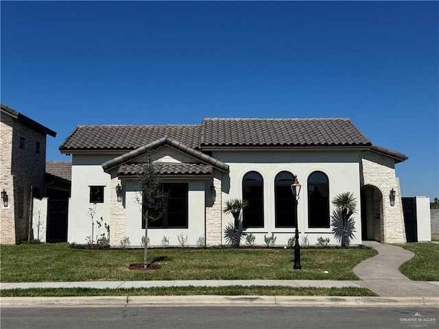 mediterranean / spanish house with a tile roof, a front lawn, and stucco siding