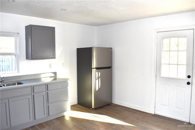 kitchen featuring dark wood-style floors, gray cabinets, freestanding refrigerator, and a sink