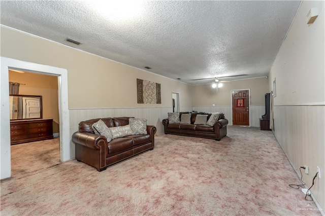 living room featuring a textured ceiling, light colored carpet, ceiling fan, and wood walls