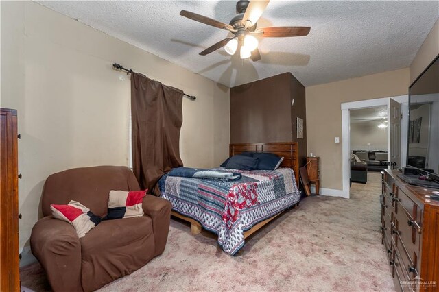 bedroom featuring ceiling fan, light carpet, and a textured ceiling