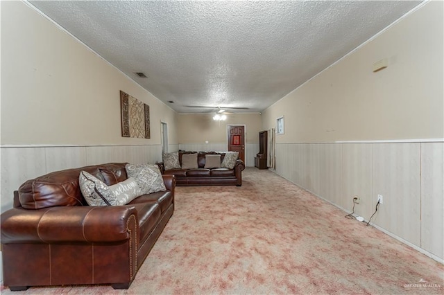 carpeted living room with wood walls, ceiling fan, and a textured ceiling