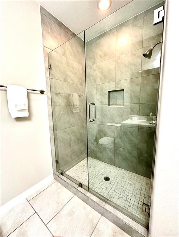 bathroom with a shower with shower door and tile patterned flooring