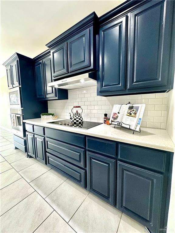 kitchen featuring blue cabinets, light tile patterned floors, black electric stovetop, oven, and backsplash